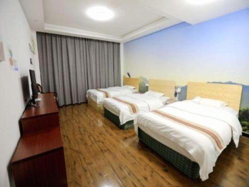 a hotel room with three beds and a television at Shell Linzhi Bayi Area G318 Shuangyong Road Hotel in Nyingchi
