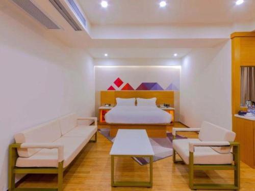 a bedroom with a bed and two chairs and a table at Borrman Hotel Zhanjiang Shimao Building High-speed Railway Station in Zhanjiang