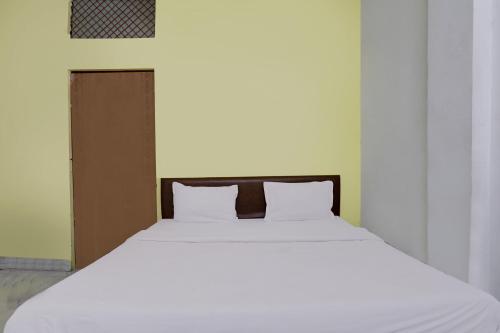 a white bed with two pillows in a room at Hotel O Raghav Residency in Ghaziabad