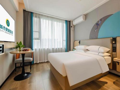 a bedroom with a large white bed and a table at City Comfort Inn Guilin Jiatianxia Square International Conferences & Exhibition Center in Guilin