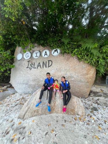 two people sitting on a rock in front of a sign at Nipah Bay Villa in Pangkor