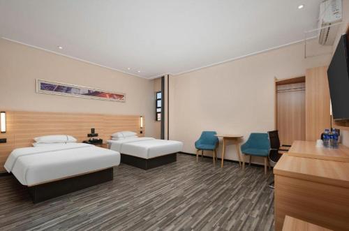 a hotel room with two beds and a table and chairs at City Comfort Inn Huangshi Bei Station in Huangshi
