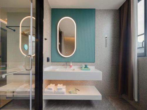 une salle de bain avec un lavabo et un miroir dans l'établissement City Comfort Inn Hechi Yizhou Erqiao, à Qingyuan