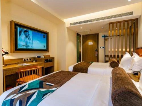 a hotel room with two beds and a flat screen tv at James Joyce Coffetel· Xianyang Renmin Road Central Square Store in Xianyang
