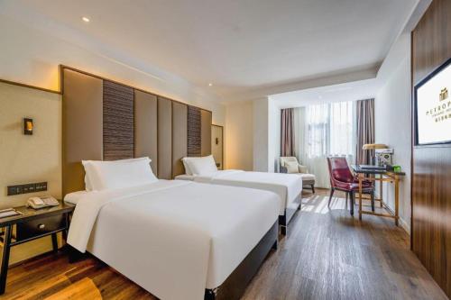 a hotel room with two beds and a desk at Jinjiang Metropolo Haikou East High Speed Railway Station Normal University in Haikou