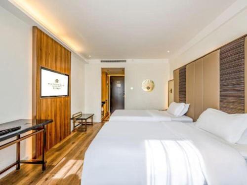 a hotel room with two beds and a flat screen tv at Jinjiang Metropolo Haikou East High Speed Railway Station Normal University in Haikou