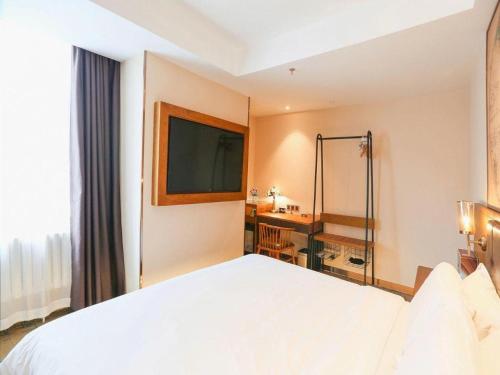 a bedroom with a large white bed and a desk at James Joyce Coffetel Changchun People's Square in Changchun