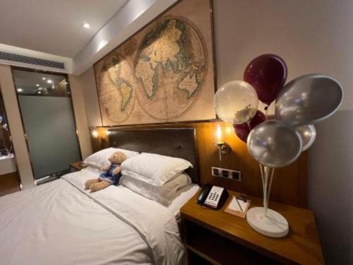 a stuffed teddy bear sitting on a bed with balloons at James Joyce Coffetel Changchun People's Square in Changchun