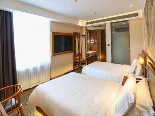 a hotel room with two beds and a television at James Joyce Coffetel Changchun People's Square in Changchun