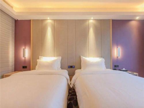 two beds in a hotel room with white sheets at Lavande Hotels Wuhan Guanggu Yangjiawan Metro Station in Wuhan