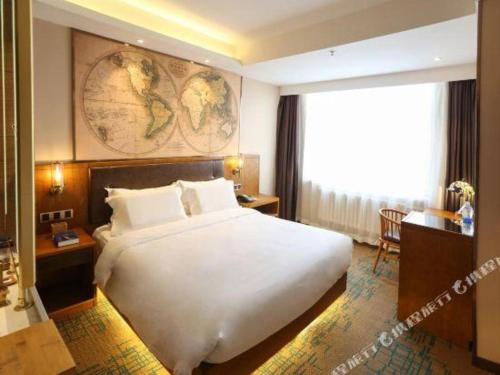 a hotel room with a large white bed and a desk at James Joyce Coffetel Changchun People's Square in Changchun