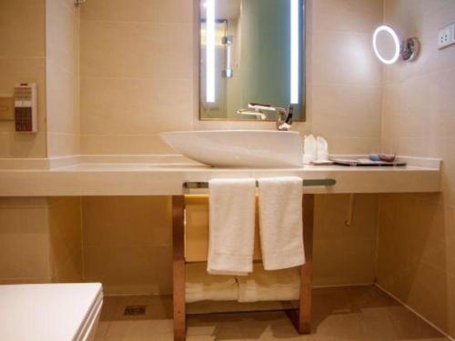 a bathroom with a sink and a mirror and towels at Lavande Hotels Wuhan Guanggu Yangjiawan Metro Station in Wuhan