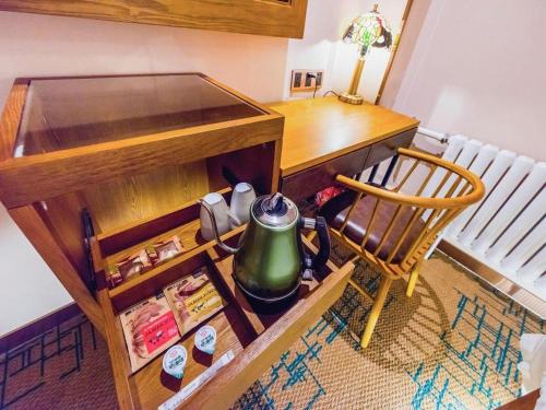 a desk with a tea pot and a chair next to a table at James Joyce Coffetel Changchun People's Square in Changchun