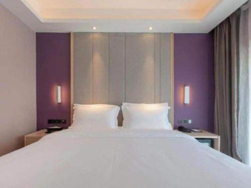 a large white bed in a room with purple walls at Lavande Hotels Wuhan Guanggu Yangjiawan Metro Station in Wuhan
