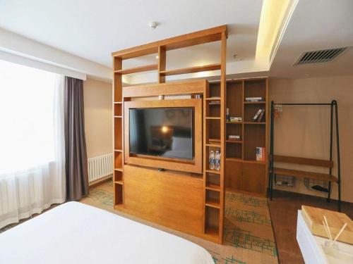a room with a bed and a flat screen tv at James Joyce Coffetel Changchun People's Square in Changchun