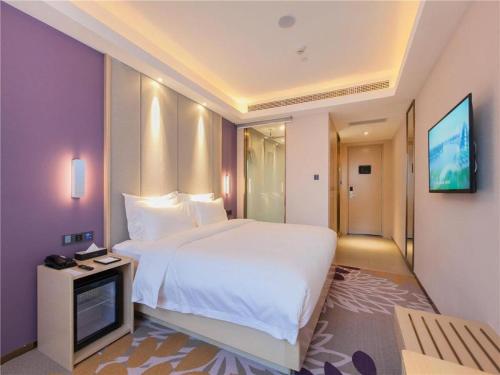 a bedroom with a large white bed and a tv at Lavande Hotels Wuhan Guanggu Yangjiawan Metro Station in Wuhan