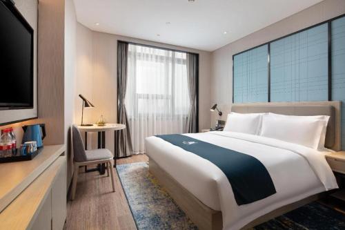 a hotel room with a large bed and a tv at Echarm Hotel Shenyang Zhongjie North Station Metro Station in Shenyang