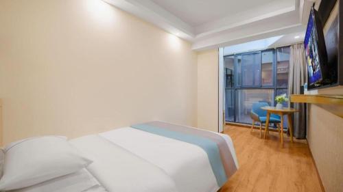 a bedroom with a white bed and a balcony at City Comfort Inn Kunming High Speed Railway South Station Yongxin Harvard in Kunming