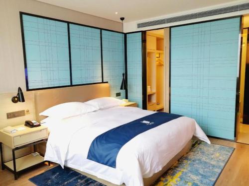 a bedroom with a large bed with blue windows at Echarm Hotel Kunming High-speed Railway South Station Chunrong Street Metro Station in Kunming