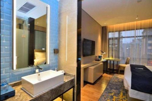 a bathroom with a sink and a bed and a mirror at Echarm Hotel Kunming High-speed Railway South Station Chunrong Street Metro Station in Kunming