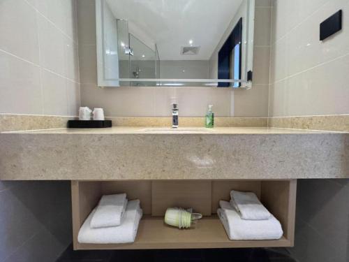 a bathroom with a sink and a mirror and towels at City Comfort Inn Shiyan Wudang Mountain in Danjiangkou