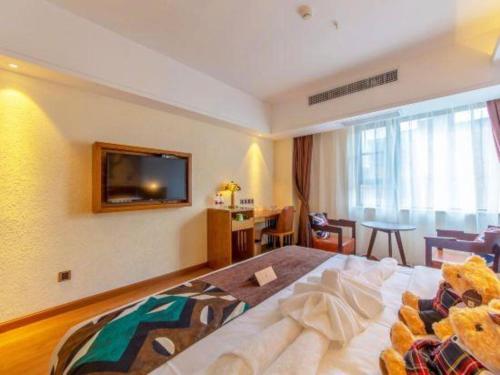 a hotel room with a bed and a television on the wall at James Joyce Coffetel Kunming Railway Station Huancheng Nan Road Metro Station in Kunming