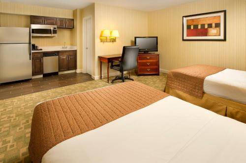 a hotel room with two beds and a desk and a kitchen at American Inn of Bethesda in Bethesda