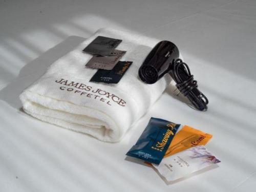 a towel with a bottle of wine and a book at James Joyce Coffetel Kunming Railway Station Huancheng Nan Road Metro Station in Kunming