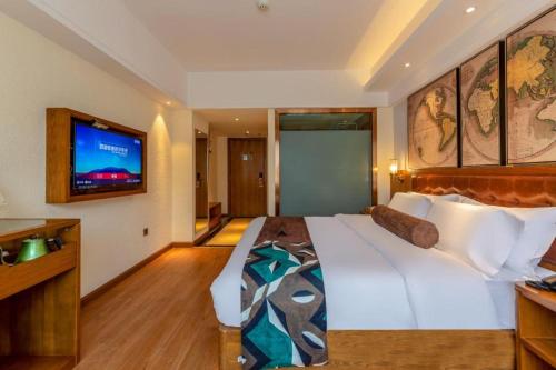 a bedroom with a large white bed and a television at James Joyce Coffetel Kunming Railway Station Huancheng Nan Road Metro Station in Kunming