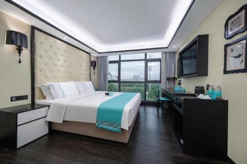 a bedroom with a bed and a desk and a television at Xana Hotelle Shenzheng South Station Foxconn in Shenzhen
