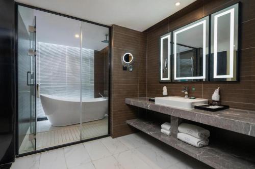 a bathroom with a tub and a sink and a shower at Xana Hotelle Shenzheng South Station Foxconn in Shenzhen