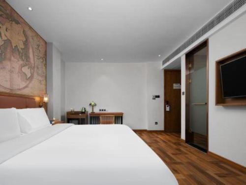 a bedroom with a large white bed and a flat screen tv at James Joyce Coffetel Luoyang Longmen High-speed Railway Station Baolong Plaza in Luoyang