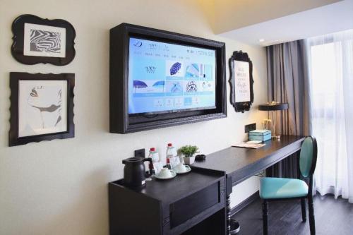 a room with a desk with a television on the wall at Xana Hotelle Shenzheng South Station Foxconn in Shenzhen