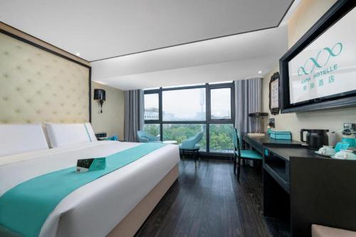a hotel room with a large bed and a flat screen tv at Xana Hotelle Shenzheng South Station Foxconn in Shenzhen