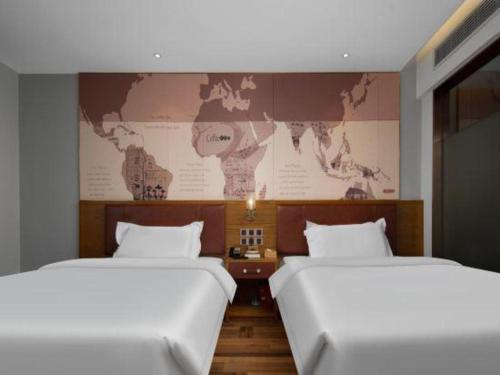 two beds in a room with a map on the wall at James Joyce Coffetel Luoyang Longmen High-speed Railway Station Baolong Plaza in Luoyang