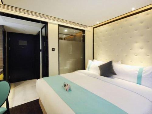 a bedroom with a large white bed with a blue bench at Xana Hotelle Shenzheng South Station Foxconn in Shenzhen