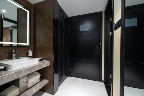 a bathroom with a sink and a black door at Xana Hotelle Shenzheng South Station Foxconn in Shenzhen