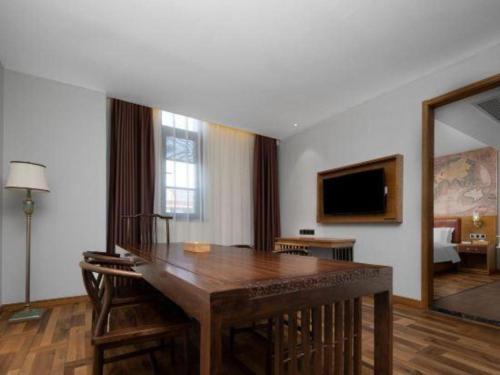 a room with a wooden table and a living room at James Joyce Coffetel Luoyang Longmen High-speed Railway Station Baolong Plaza in Luoyang