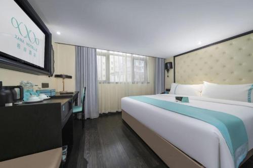 a hotel room with a large bed and a flat screen tv at Xana Hotelle Shenzheng South Station Foxconn in Shenzhen