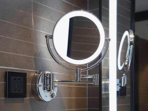 a mirror hanging on a bathroom wall next to a wall at Xana Hotelle Shenzheng South Station Foxconn in Shenzhen