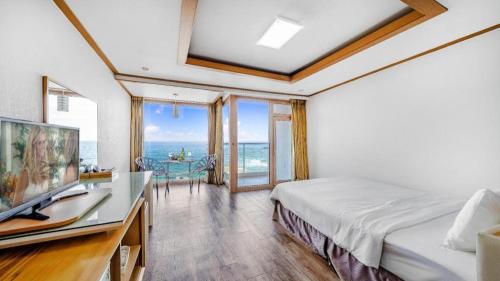 a bedroom with a bed and a desk with a television at Gangneung Four Season Hotel and Pension in Kyŏngp'o-mal