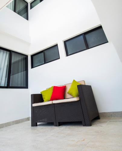 a wicker couch with three colorful pillows on it at Yuum Ha Boutique Hotel in Río Lagartos