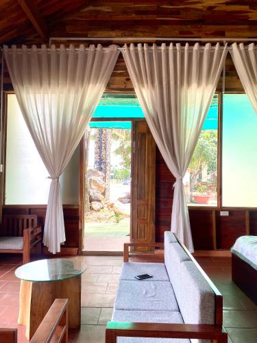 a living room with curtains and a couch and a table at An Bình Home in Ha Tien