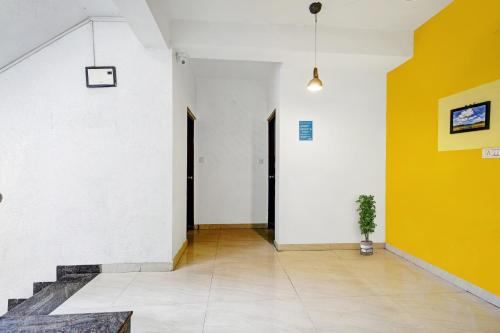 a hallway with yellow and white walls and a potted plant at Hotel O VSV Avenue Hennur in Bengaluru