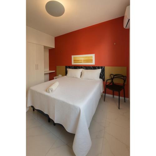 a bedroom with a white bed with a red wall at 958 Golden Flat Fortaleza in Fortaleza