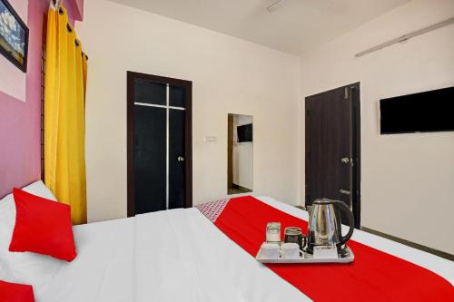 a hotel room with a bed with a red and white bedspread at Hotel O VSV Avenue Hennur in Bengaluru