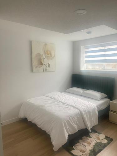 a white bedroom with a bed and a window at Your Cozy Happy Place in Calgary
