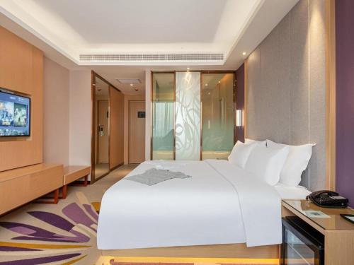 a bedroom with a large white bed and a television at Lavande Hotel Changsha South High-speed Railway Station Xiyingmen in Changsha