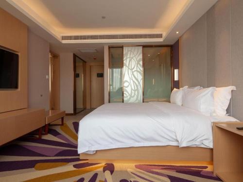 a bedroom with a large white bed and a television at Lavande Hotel Changsha South High-speed Railway Station Xiyingmen in Changsha