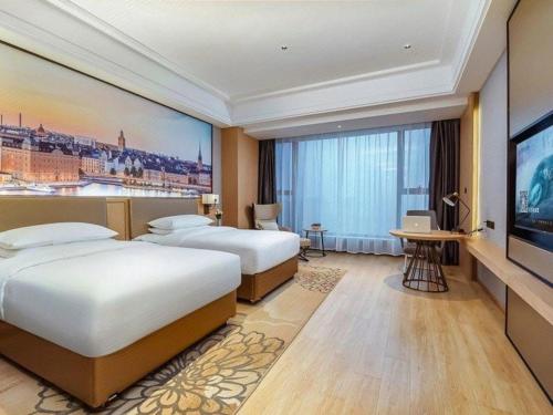 une chambre d'hôtel avec deux lits et une télévision à écran plat dans l'établissement Venus Royal Hotel Anhui Tongcheng Tongguoxiushui, à Wangguolu
